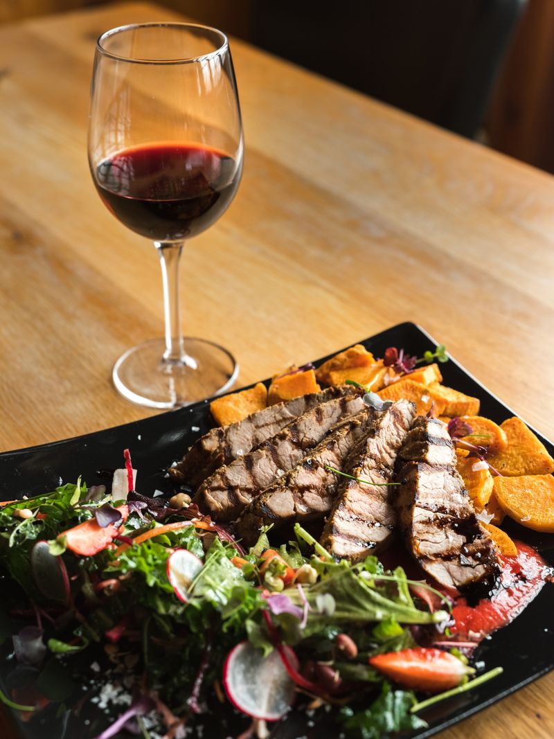 A plated steak dinner with a glass of red wine